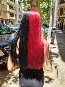 Mujer con pelo bicolor mitad rojo y mitad negro de Peluqueros de Moda